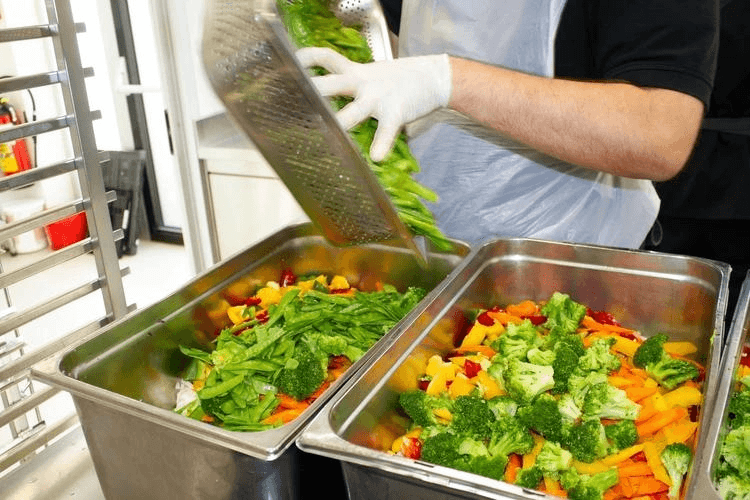 Food service staff preparing fresh vegetables for commercial kitchens and hospitality customers.
